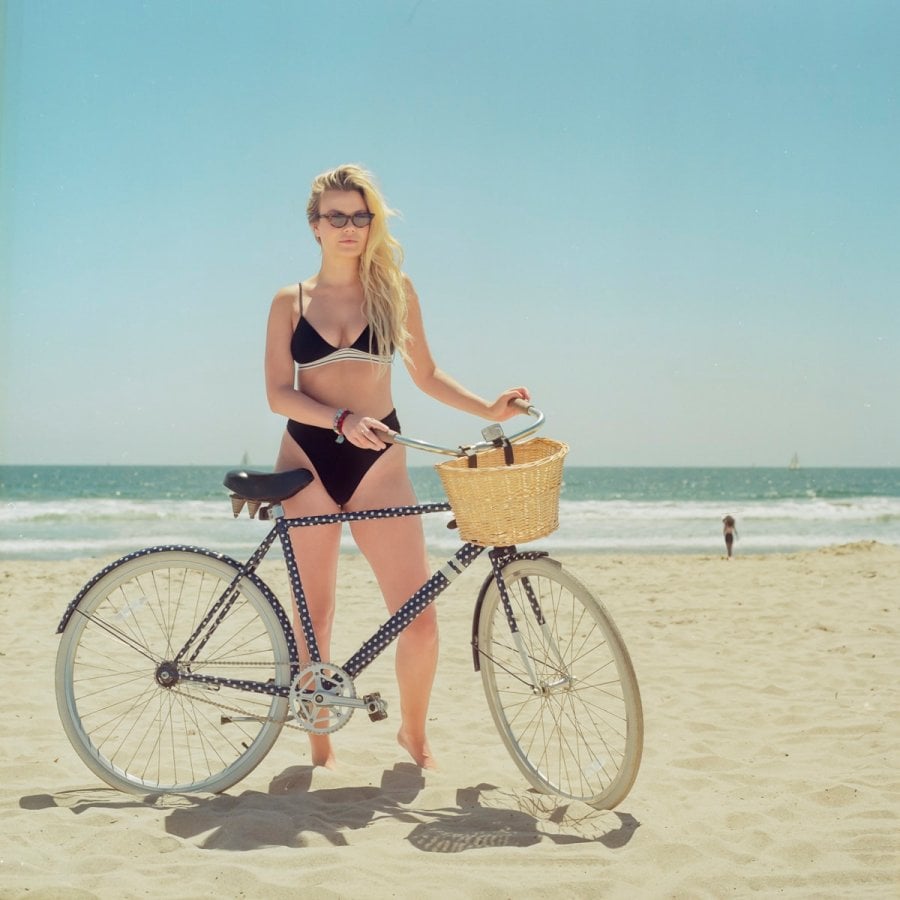 A portrait of a woman with her bike on the beach
