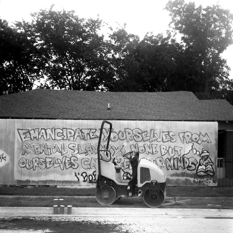 A road roller in front of graffiti quoting by Bob Marley