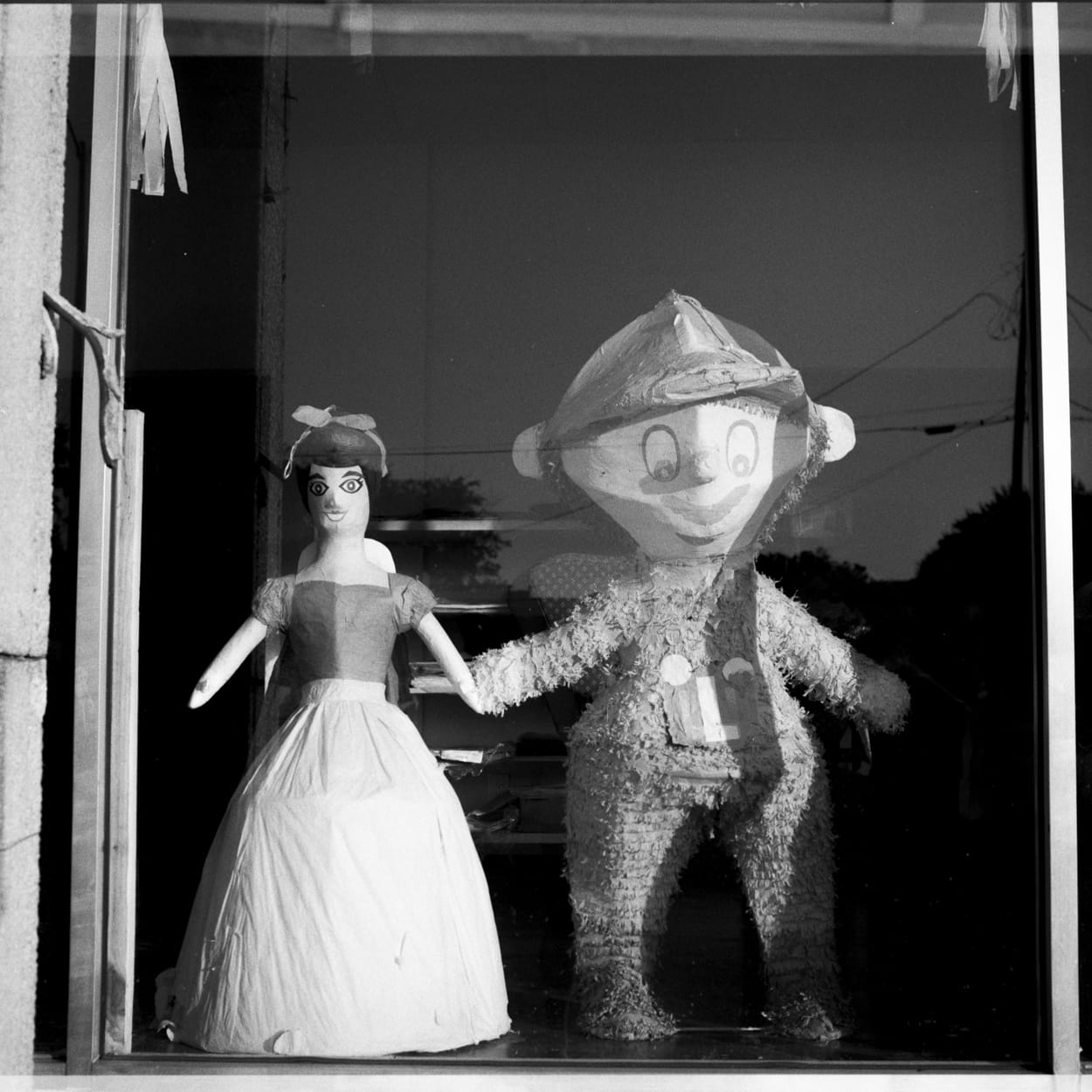 Snow White and Mario piñatas holding hands like two lovers in a window display 