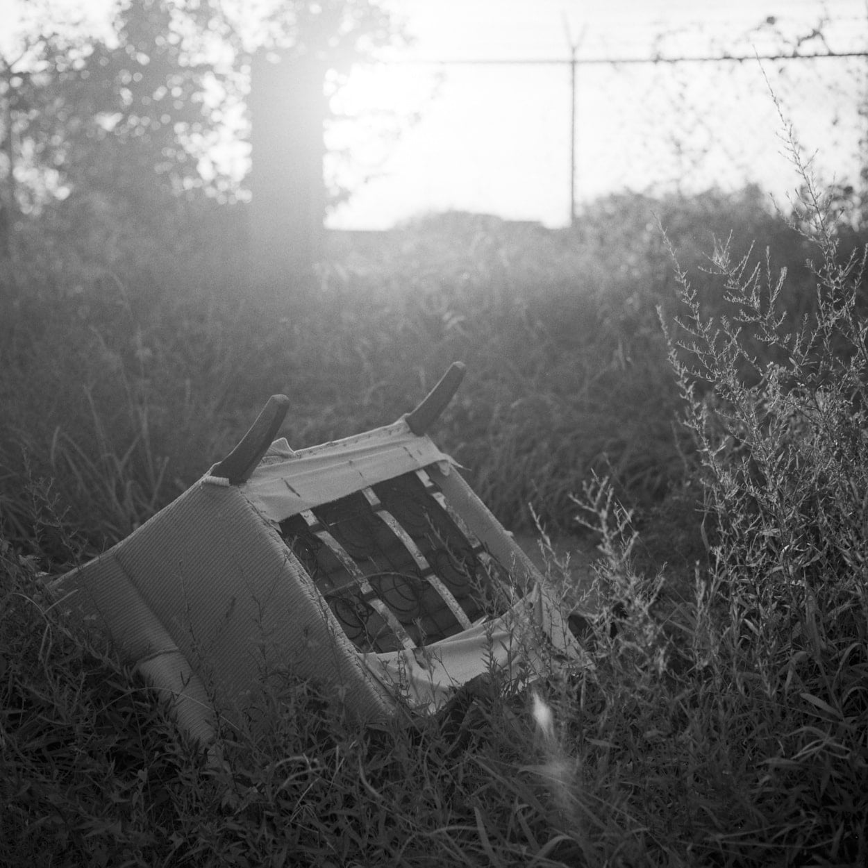 A discard chair in grass on the side of the road