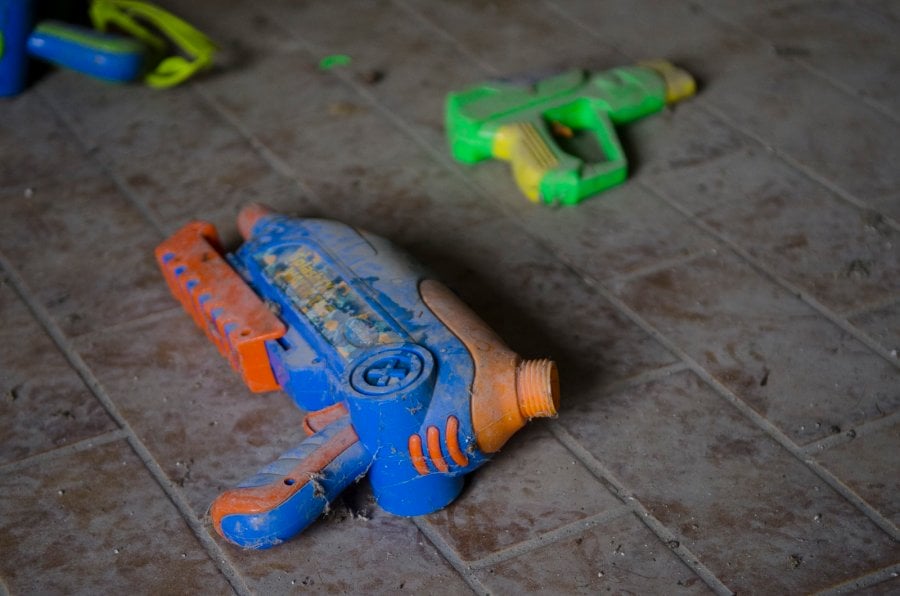 A dusty toy gun on the ground in an abandoned house 