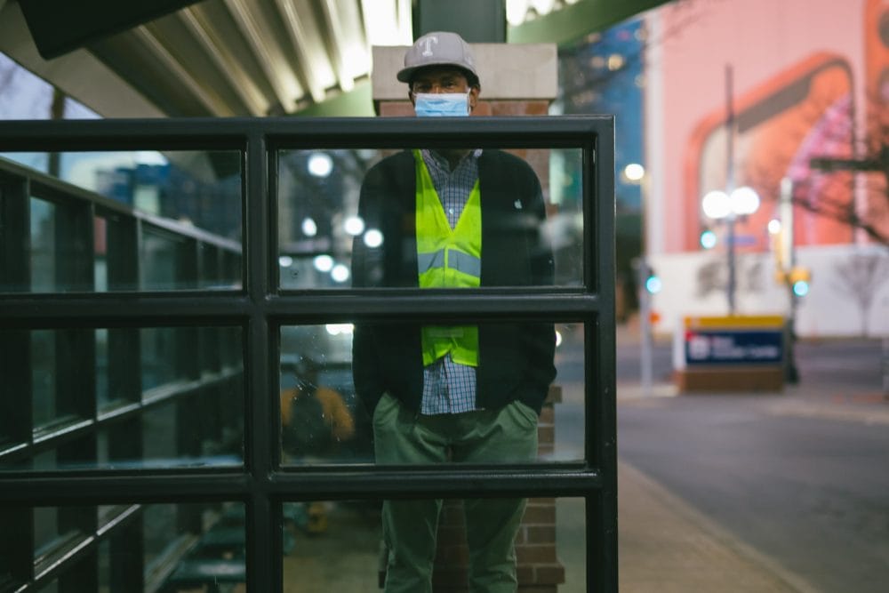 A city worker standing behind a glass wall at a bus stop