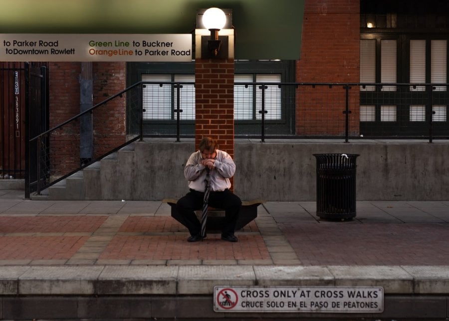 A man sitting alone at a train station in Dallas