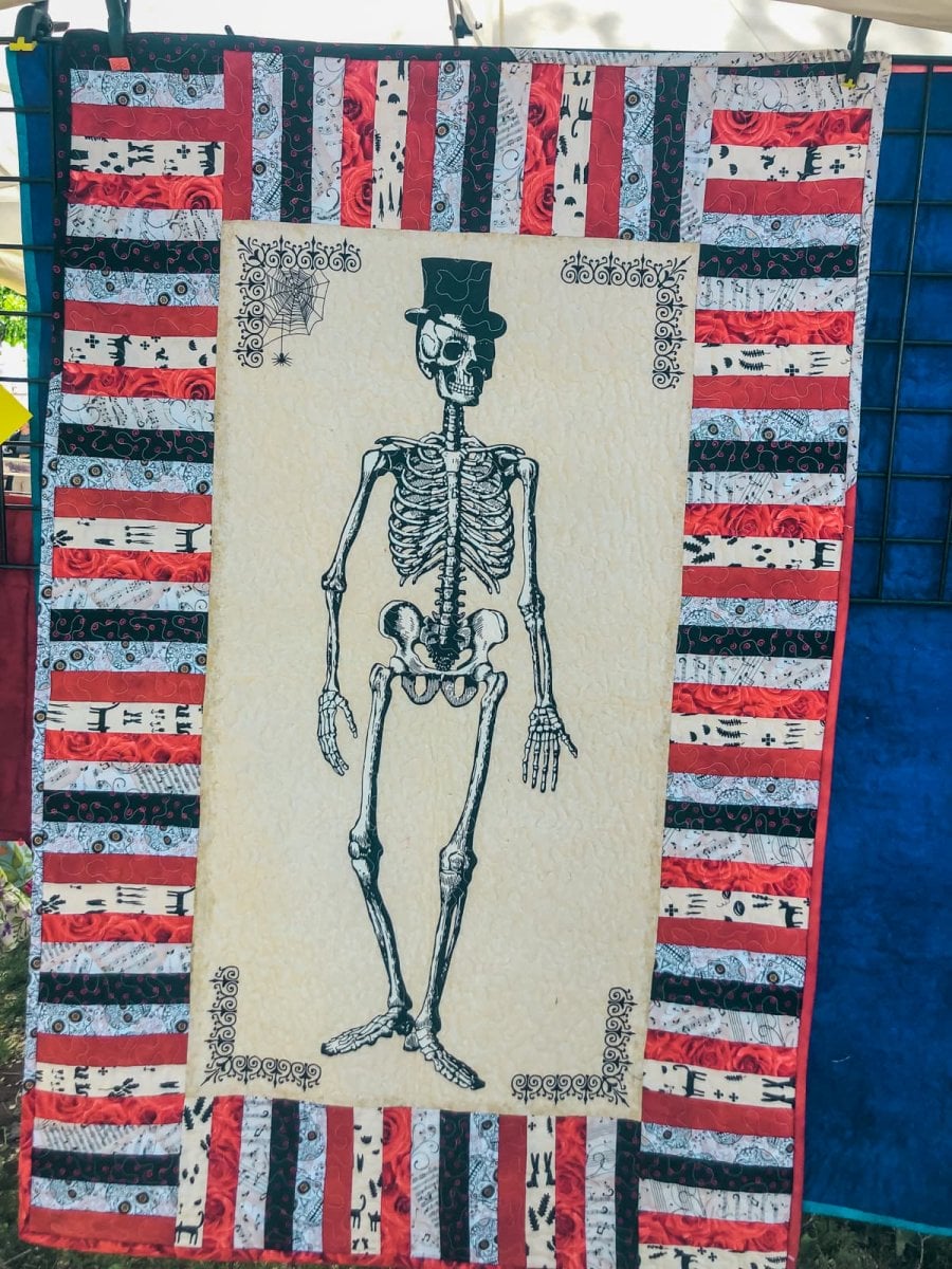 A blanket with a skeleton in a top hat on it