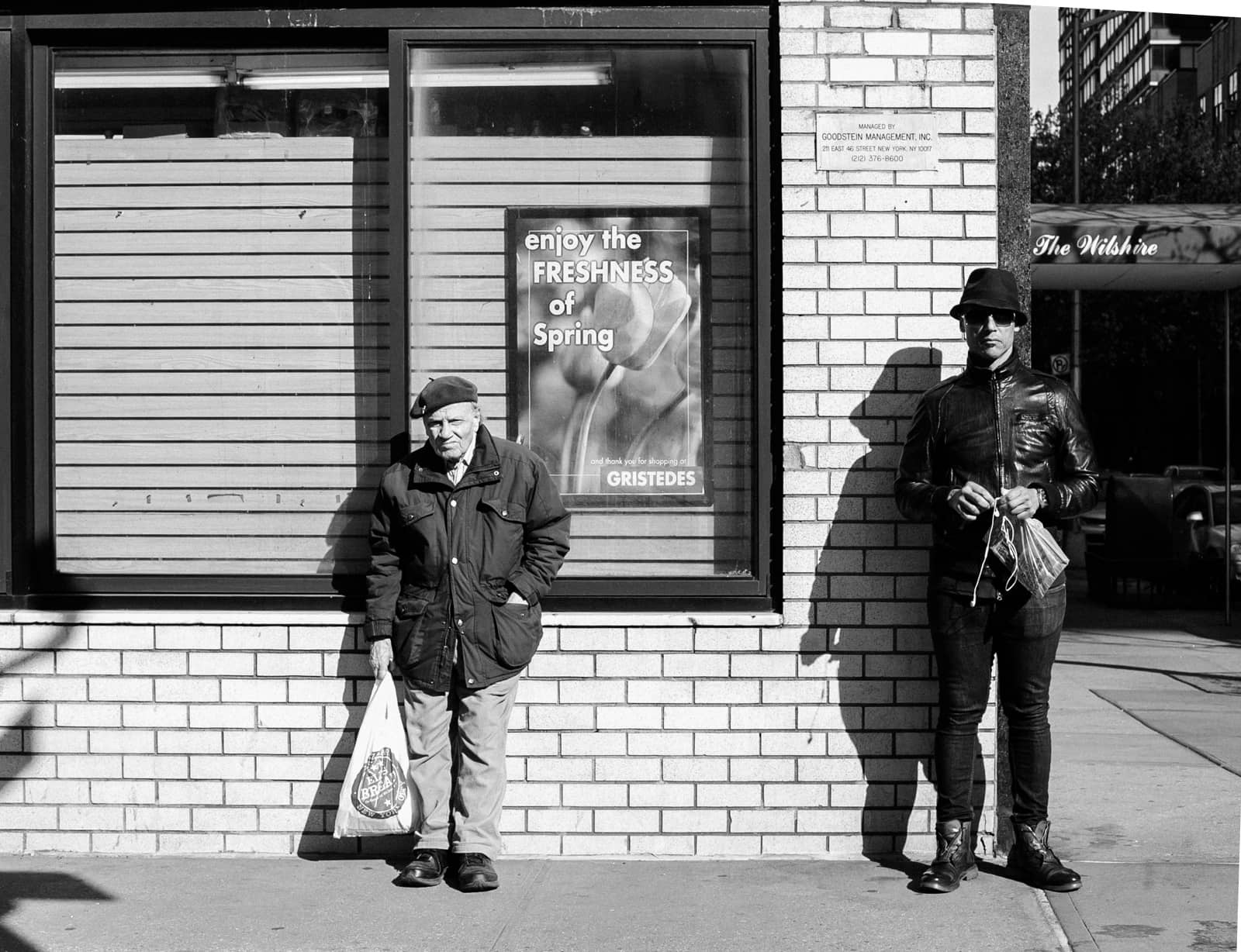 An older man and a young main waiting for the bus