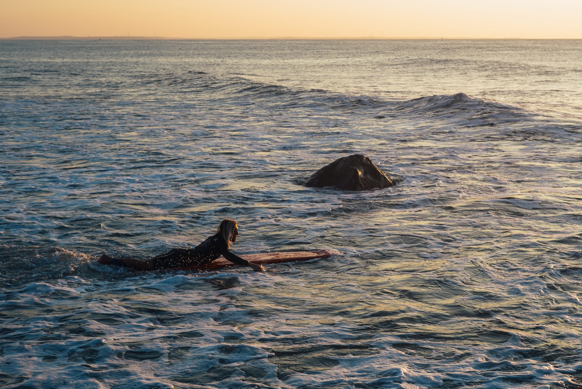 A surfer at Point Judith, Narragansett, Rhode Island during sunrise