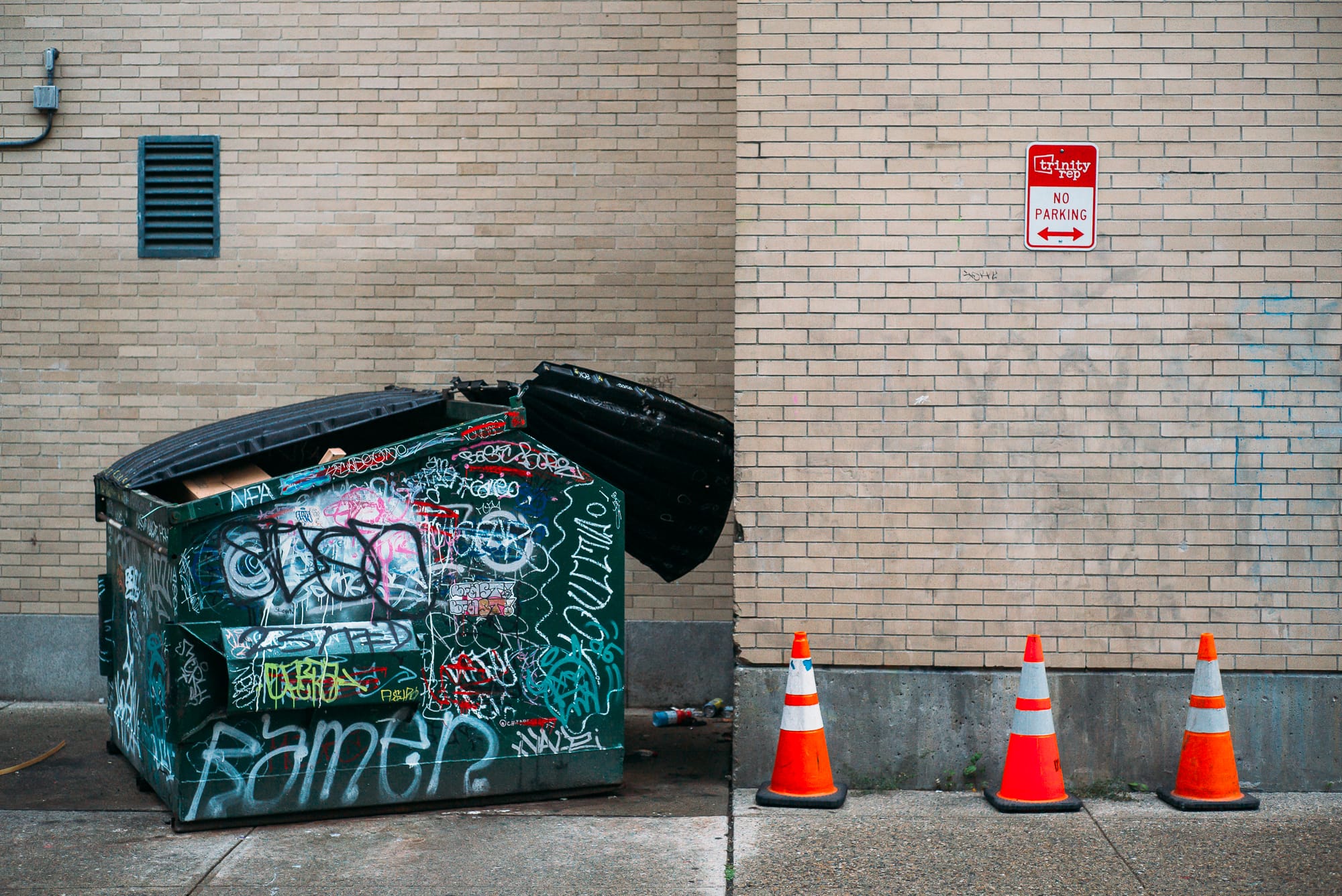 A dumpster covered with graffiti and traffic cones in downtown Providence